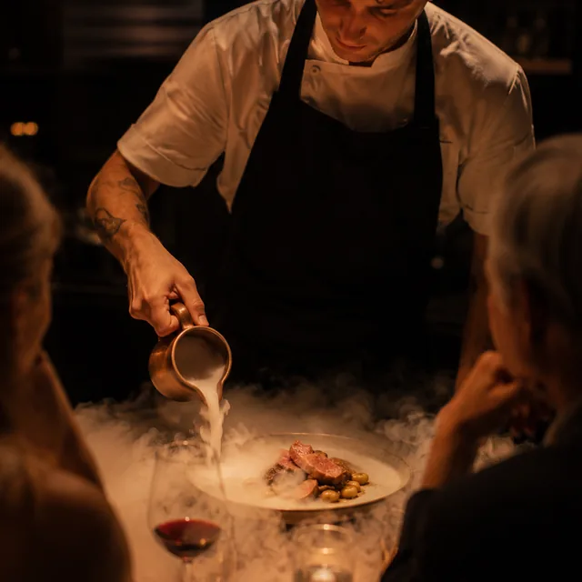 Cocinero activando una experiencia con niebla junto a la mesa