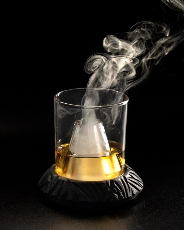 Vaso de destilado con una pieza cónica que emite humo desde el centro