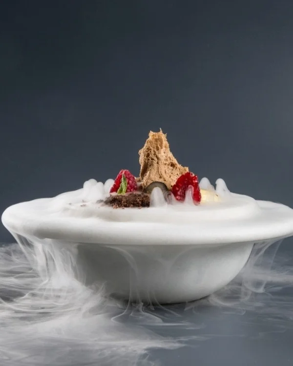 Postre servido en plato hondo con la niebla desbordando por el canto